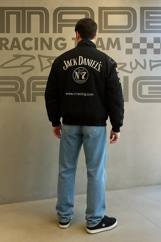 Man wearing black Jack Daniel's racing jacket and light blue jeans standing indoors