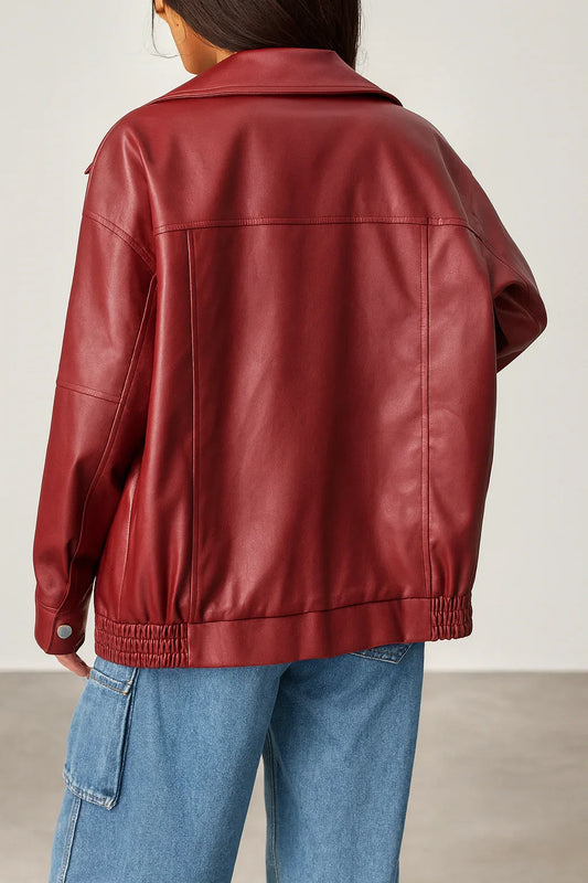 Back view of a woman in a maroon faux leather oversized jacket and blue cargo jeans