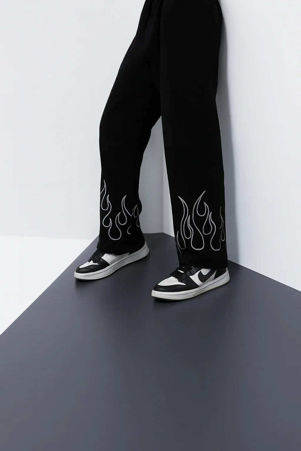 Black streetwear cargo pants with white flame print and black sneakers, urban fashion