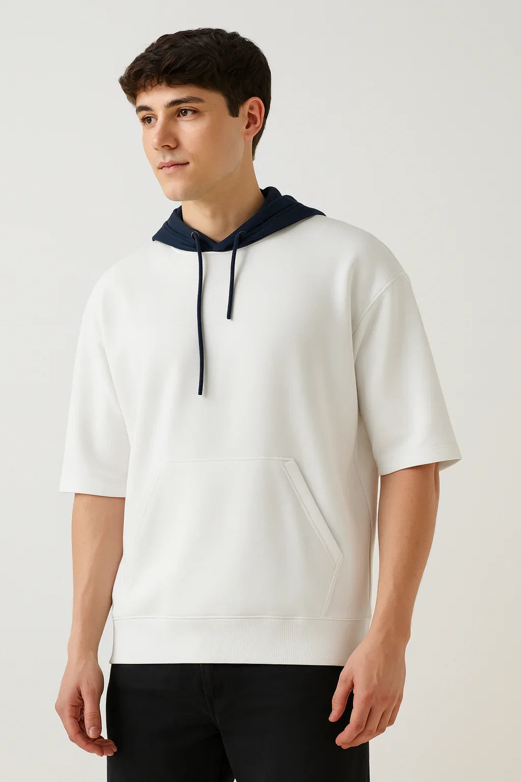 Man wearing a white short sleeve oversized hoodie with kangaroo pocket and black hood